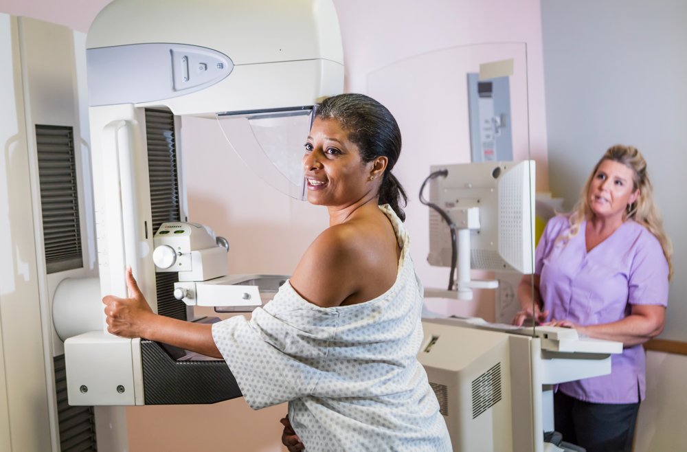 A woman completing a mammogram in a patient room.